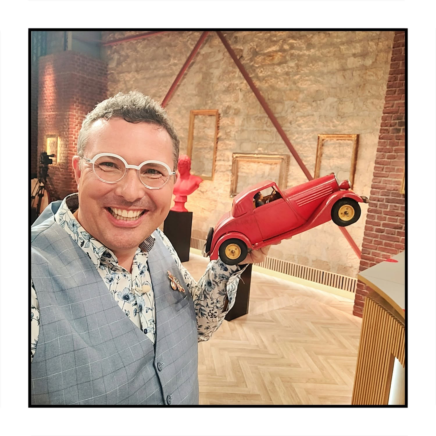 Sébastien Delcampe souriant avec une voiture de collection rouge sur le plateau d’Affaire conclue